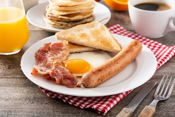Traditional American breakfast with fried egg,toast,bacon and sausage on wooden table	