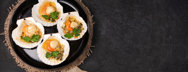 banner with baked scallops with caviar and creamy garlic sauce on a black textured background with space for your text. Top view. Copy space.