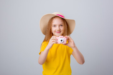little girl in hat traveler holds a camera on a white background