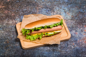 Delicious homemade hot dog with cucumber, tomato and onion. Hot frankfurter. View from above. Rusty metal background. 