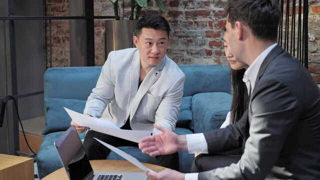 Asian businessman presenting document foreign colleagues sitting in meeting room persuading investors influencing on clients decision with negotiation selling skill convincing partners to make deal.
