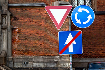 the sign is circular motion, give way and end of a one-way road on the background of the building