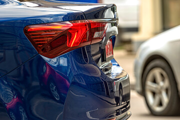 rear half with rear lights of a parked car on the side of the street, vehicle exterior details