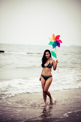 Woman Holding Pinwheel Toy While Walking At Beach Against Sky