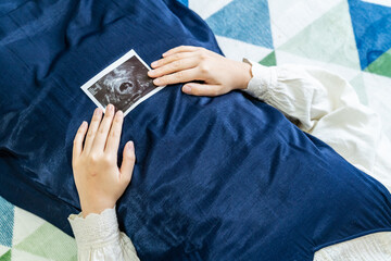 赤ちゃんのエコー写真を持った妊婦の写真。妊娠中のイメージ。