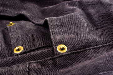 clothing items stonewashed cotton fabric texture with seams, clasps, buttons and rivets, macro