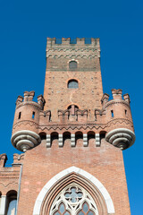 The famous tower in the centre of Asti, Italy, named "Torre Comentina". This medieval and ancient tower is made of red bricks. Blue sky on the background.