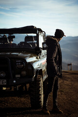 Young man by his pickup truck admiring the view from the mountaintop