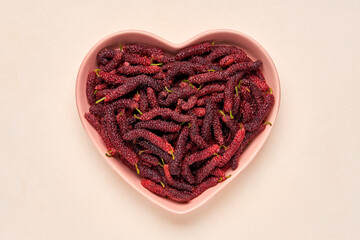 Fresh mulberries in a hearth shaped plate . Top view
