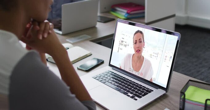 African american woman having a video conference on laptop with female office colleague at office
