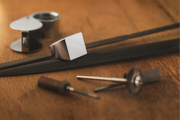 Empty signet silver ring and jeweler tools on wooden antique table. Tamplate for engraver, mockup.