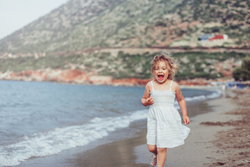 Little adorable girl plays on sea coast. Summer time, vacation concept