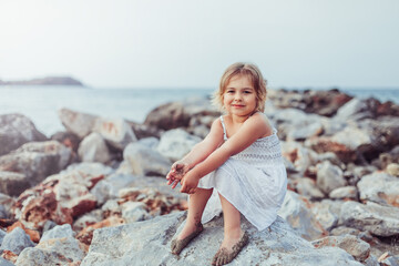 Little adorable girl plays on sea coast. Summer time, vacation concept