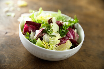 Healthy mixed green salad in a white bowl