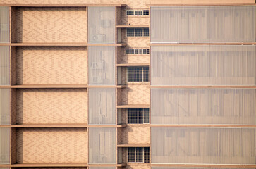 Clean geometric wall colored beige of a high rise building with windows of houses in suburban Mumbai.