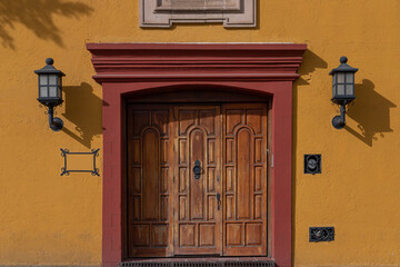 A yellow wall and a beautiful wooden door in Mexico. Traditional Mexican exterior