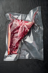 T bone or porterhouse dry aged  steak in vacuum pack , on black stone background, top view flat lay
