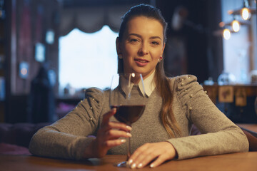 Hand of a young beautiful woman holding a glass of wine indoors of a stylish wine restaurant