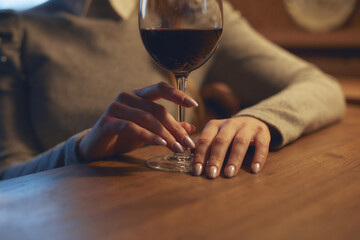 Hand of a young beautiful woman holding a glass of wine indoors of a stylish wine restaurant