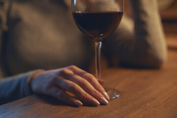 Hand of a young beautiful woman holding a glass of wine indoors of a stylish wine restaurant