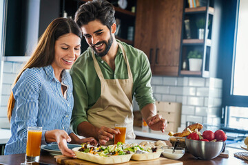 Portrait of happy couple cooking together in the kitchen at home.