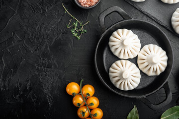 Raw dumplings Dim Sum, in frying cast iron pan, on black stone background, top view flat lay, with copy space for text