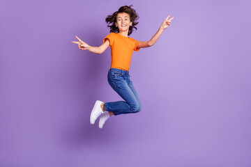 Full length body size view of attractive cheerful boy jumping showing v-sign isolated over violet purple color background