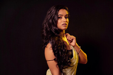 Naklejka premium Young Indian fashion model in Saree on black background. Looking at camera. Serious look