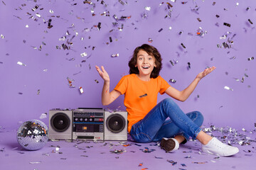 Full length body size photo happy boy sitting near tape recorder disco ball with flying confetti...