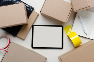 Top view of empty screen of tablet, cardboard boxes, staionary on the desk.Concept of delivery...