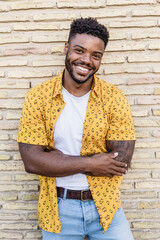 Portrait of a handsome black man smiling with a brick background
