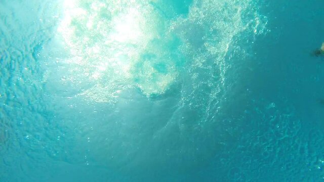 View From Bottom Of Pool To Young Man Jumping Into Crystal Clear Water. Guy Refreshing In Basin During Resting On Resort. Male Caucasian Enjoying Summer Vacation. Underwater Footage. Slow Motion