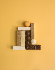 Many kinds of sweet food - candy, warfers, marshmallow and cookies as geometric composition on yellow paper background