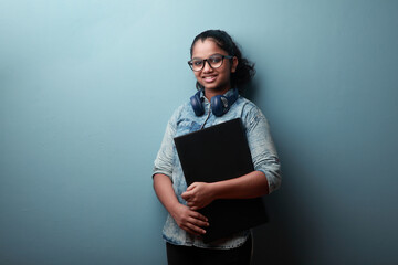 Happy girl of Indian origin holds a laptop computer 