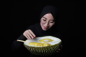 Asian woman eating durian fruit on black background.