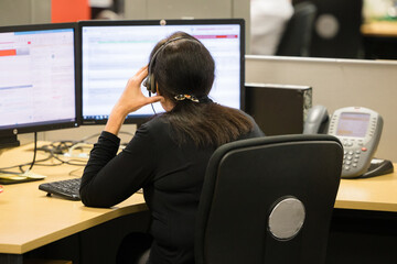 Call centre worker talks on the telephone facing a computer screen