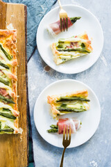 Step by step  recipe preparation of an asparagus and speck tart made with egg yolk, cream , parmisan , brisee pasta, speck and asparagus. prepared cooked and served, top view, flatlay composition