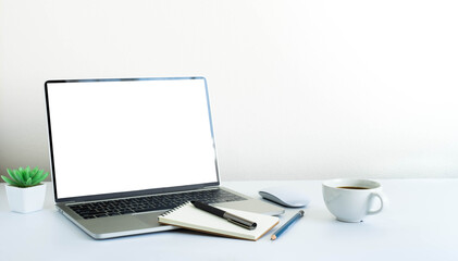 Fototapeta premium Laptop computer blank screen on white office desk table with coffee cup and notebook, mouse computer with equipment office supplies. Business and finance concept. Workplace, Flat lay with copy space.
