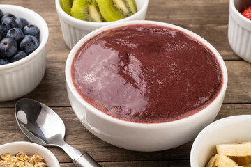 Brazilian typical acai bowl with fruits and muesli over wooden background