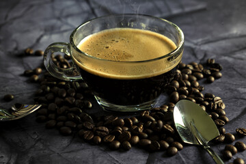 Hot espresso coffee with coffee beans on a stone background.