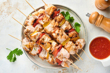 Chicken shish kebab or skewers kebab in ceramic plate, spices, cilantro herbs and vegetables on white table background. Barbecue Raw ingredients for goulash or shish kebab. Top view. Free copy space.