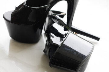Black patent leather strips / high-heeled shoes on white background