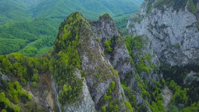 Aerial drone filming a calcareous rocky crest using the parallax effect. The calcareous peak was eroded by a river forming a narrow canyon. Beech trees manage to grow above. Buila Massif, Carpathia.