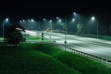Foto op Plexiglas Night highway in the light of streetlights. A truck is parked on the side of the road © VeNN