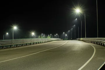 Foto op Canvas A highway with metal bumpers on the edges in the light of streetlights © VeNN