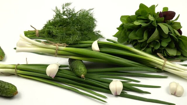Cucumbers, green onion, dill, spinach, garlic are on a white table, salad ingredients