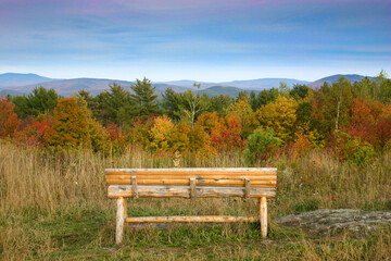Wooden bench viewpoint overlooking fall foliage and New England mountains
