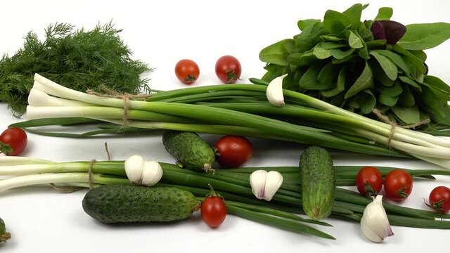 Cherry tomatoes, cucumbers, green onion, dill, spinach, garlic are on a white table, salad ingredients