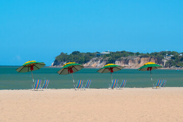 Parasols and beach chairs on Cabo Branco beach, with the Cabo Branco barrier in the background in João Pessoa, Paraiba, Brazil on April 3, 2013.