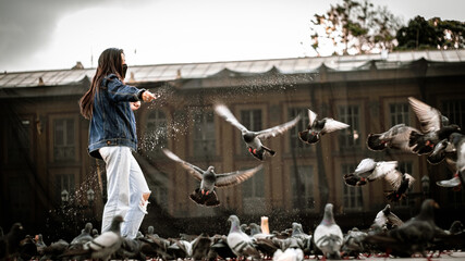 Woman feeding the birds in a square.